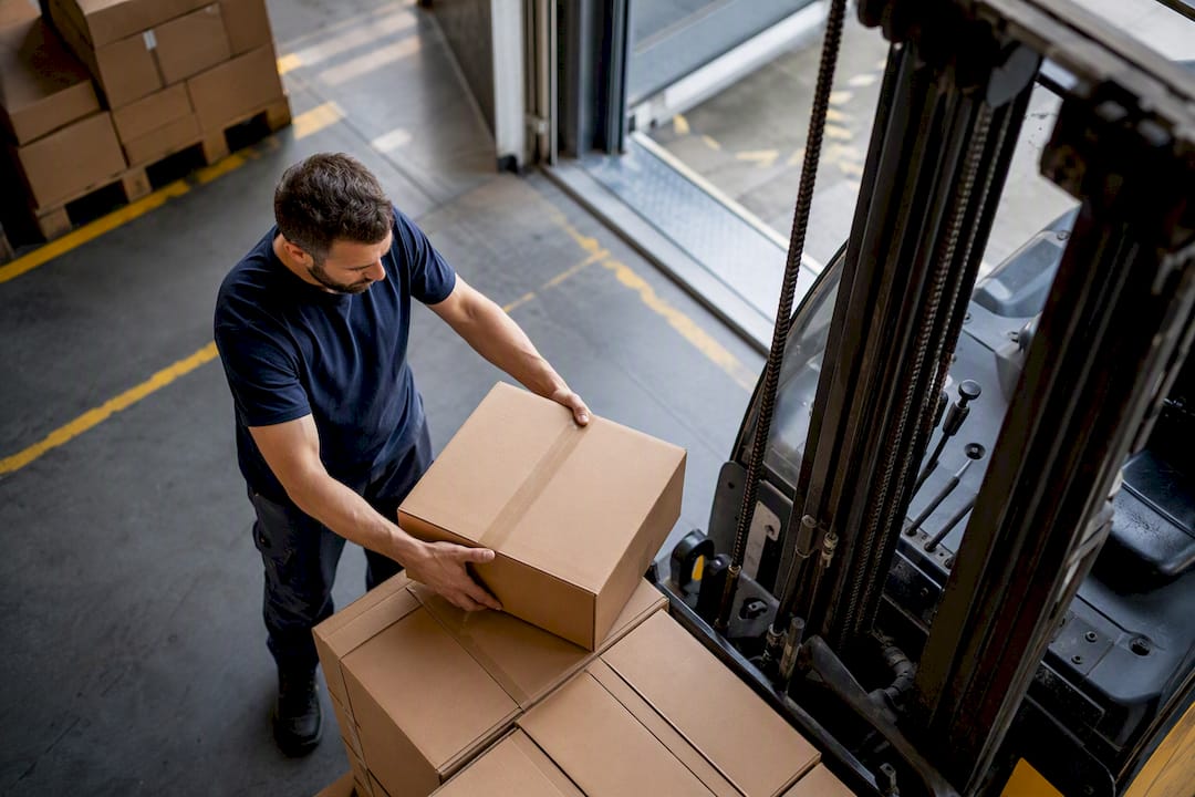 Mani che caricano scatole su un transpallet